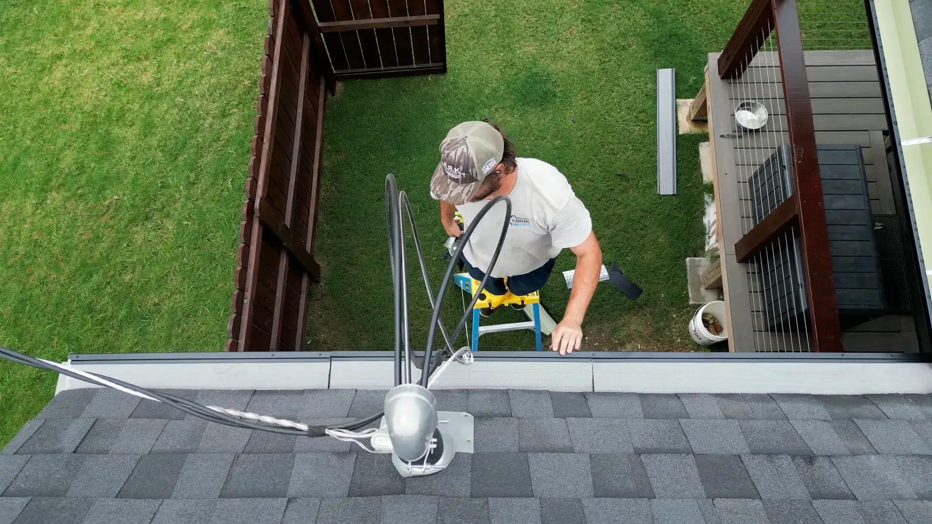 Overhead view of a technician setting a gutter guard along the shingle edge of an Arkansas home